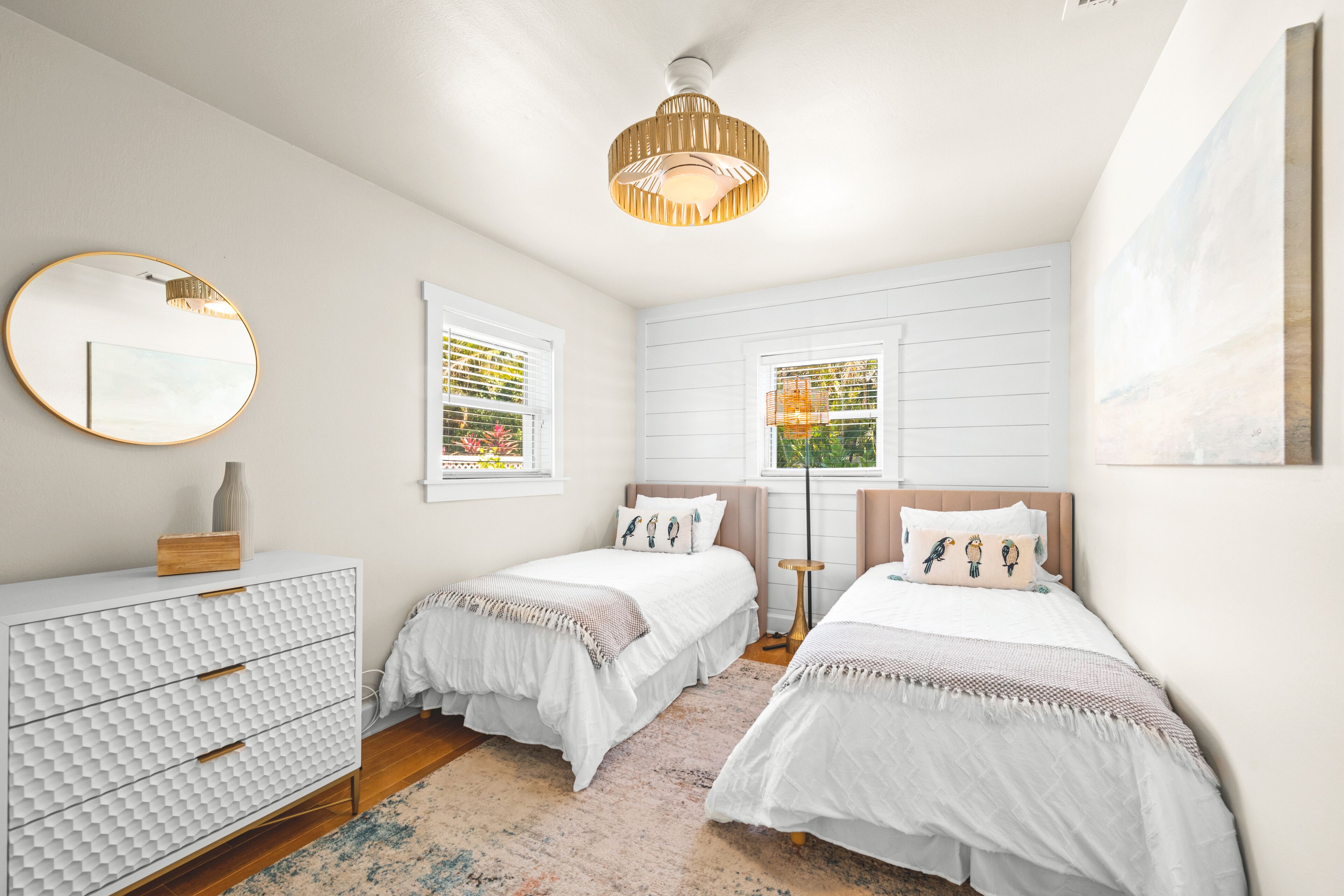 A bedroom with two beds, a dresser, a mirror, and a ceiling light fixture.