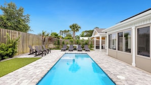 A rectangular swimming pool with a tiled deck, surrounded by lounge chairs and a wooden fence. - Point Three + Pool, Bikes, Nearby Beach & Sunroom (Panama City Beach)
