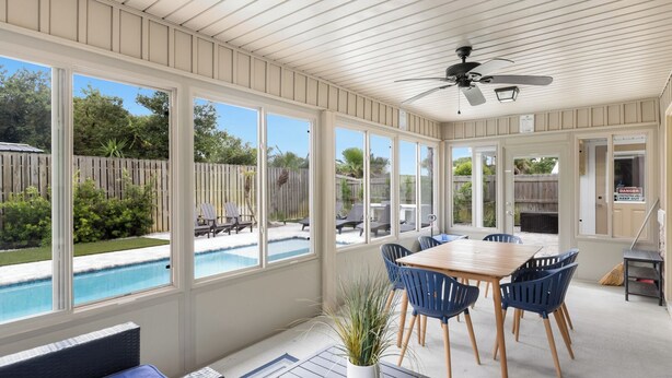 A sunroom with a pool view, a ceiling fan, and a dining area with chairs. - Point Three + Pool, Bikes, Nearby Beach & Sunroom (Panama City Beach)