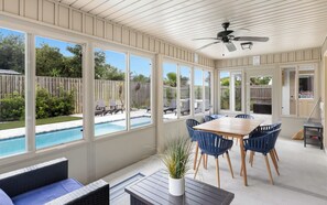 A sunroom with a pool view, a ceiling fan, and a dining area with chairs. - Point Three + Pool, Bikes, Nearby Beach & Sunroom (Panama City Beach)