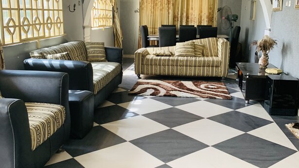 A living room with a checkered floor, two sofas, a dining table, and a chandelier. - A Charming 4-bed House in Ibese, Ikorodu (Ikorodu)