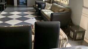 A spacious living room with a checkered floor, a sofa set, a dining table with chairs, and a TV. - A Charming 4-bed House in Ibese, Ikorodu (Ikorodu)