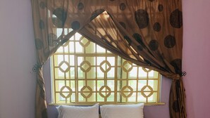 A bed with a wooden frame, white bedding, and a window with a geometric pattern. - A Charming 4-bed House in Ibese, Ikorodu (Ikorodu)