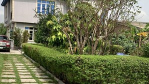 A paved pathway leading to a building with a well-maintained hedge and a parked car. - A Charming 4-bed House in Ibese, Ikorodu (Ikorodu)