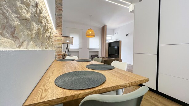 Un espace repas moderne avec une table en bois, des chaises grises et une suspension.