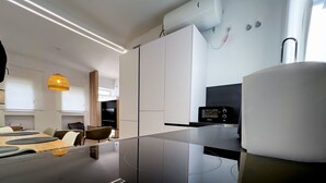 Une cuisine moderne avec des meubles blancs, un micro-ondes noir et un coin repas comprenant une table et des chaises.