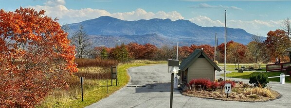 A rural road leading to a small building with a sloped roof, surrounded by autumn foliage and a mountain in the background. - 4308 Hot tub, sauna & more resort amenities Altitude Adjustment (Beech Mountain)