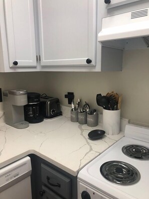 Uma cozinha com armários brancos, cafeteira, torradeira e utensílios em suportes.