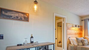 A cozy room with a wooden headboard, a bed with pillows, a table with a bottle and glasses, and a window with curtains. - 4308  Hot tub, sauna & more resort amenities  Altitude Adjustment (Beech Mountain)