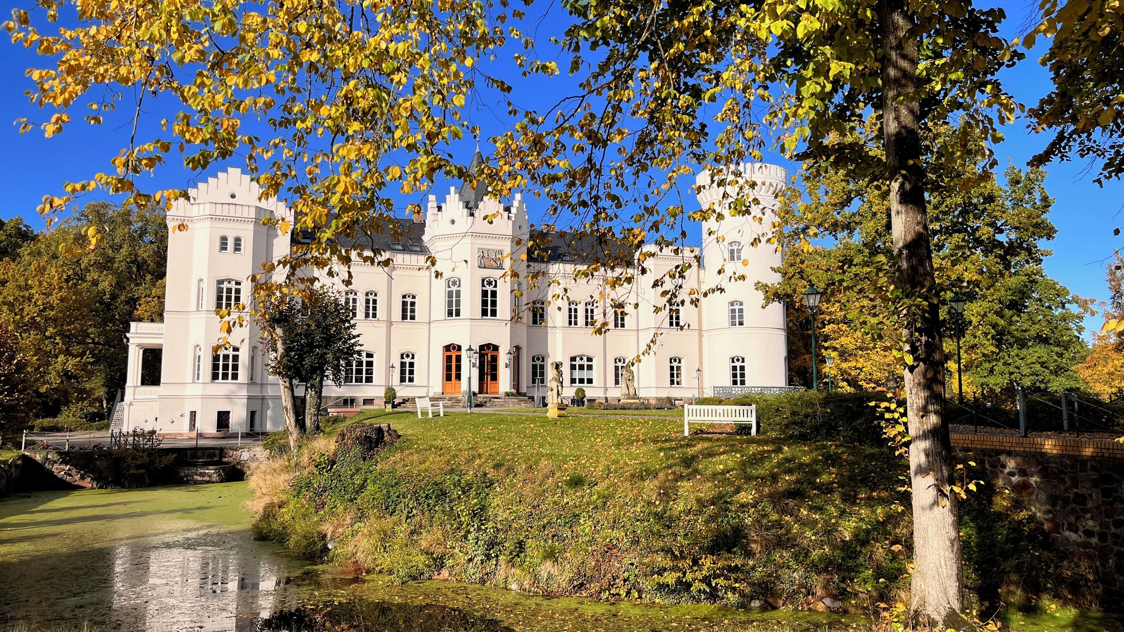 Un grand bâtiment historique doté de nombreuses tours et d’un jardin bien entretenu avec un étang.