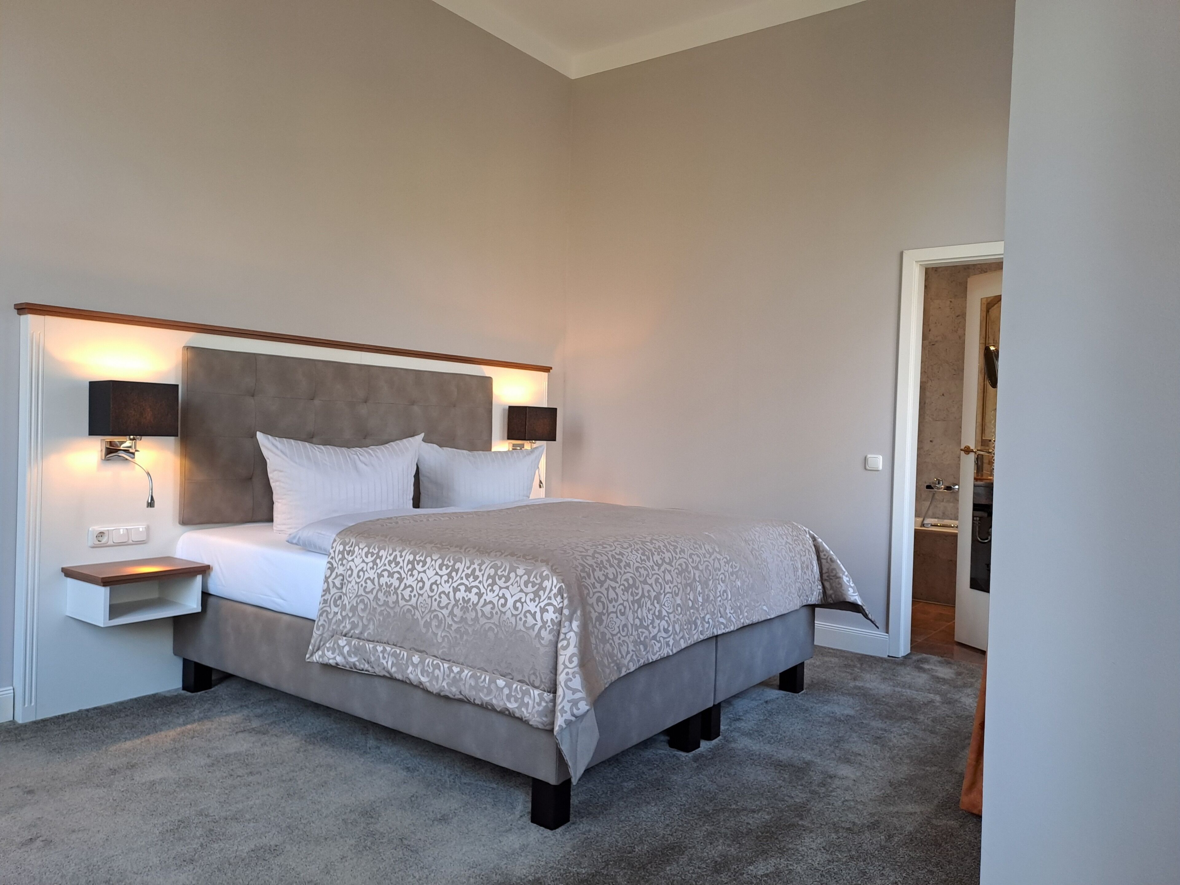 Une chambre à coucher bien rangée, avec un grand lit, des tables de chevet et une petite table de nuit.