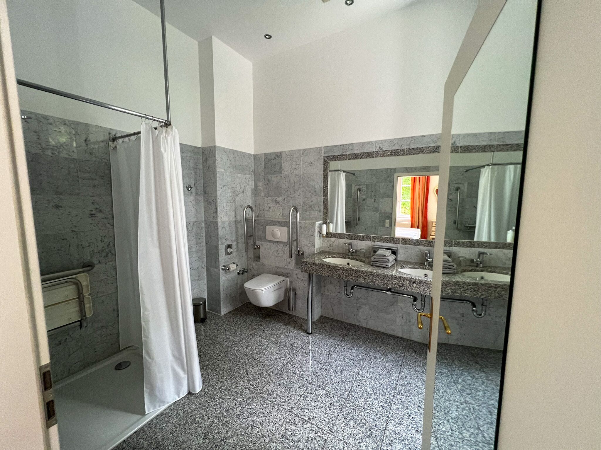 A modern bathroom with a shower, toilet, and two sinks.