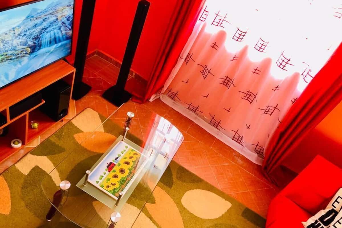 A living room with a television, a coffee table with a floral tablecloth, and a red sofa.