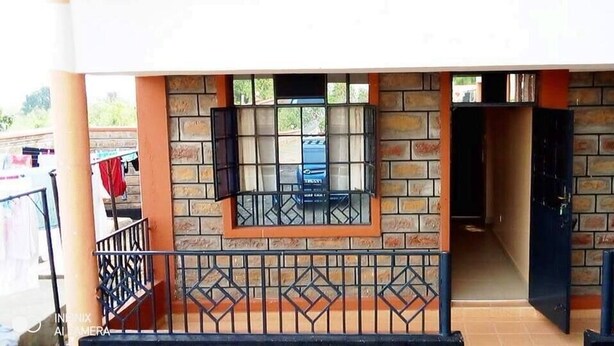A building with a brick facade, two windows with metal bars, and a gated entrance. - Stay.Plus Arujo Apartment Homa Bay (Homa Bay)