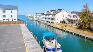 A waterfront property with a dock, a boat, and a row of houses. - Large Waterfront Townhome with Boat Dock and Pool (Ocean City)