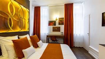 Una habitación de hotel con una cama grande, un escritorio y dos ventanas con cortinas.