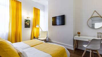 Habitación de hotel con dos camas, un escritorio, una silla, un televisor y un espejo.