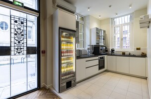 Una cocina moderna con refrigerador integrado, cafetera y ventana con contraventanas.