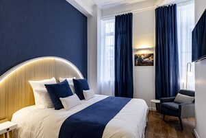 Una habitación de hotel con una cama grande, una silla, una mesita y un televisor.