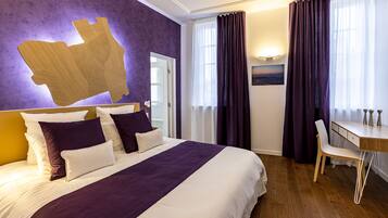 A hotel room with a large bed, a desk, and a chair.