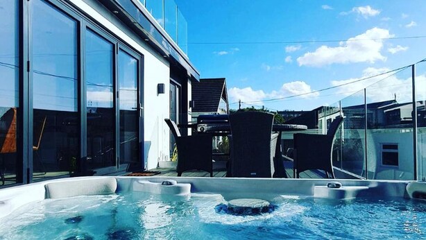 A modern building with large windows and a rooftop pool area with hot tubs. - Captivating 5-bed House in Porthleven (Helston)