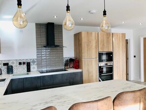 A modern kitchen with a marble island, wooden cabinets, and stainless steel appliances.