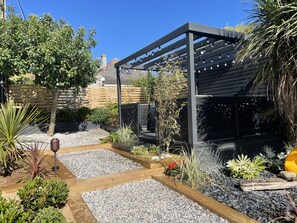 A garden with a pergola, gravel paths, and various plants. - Captivating 5-bed House in Porthleven (Helston)