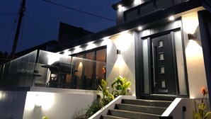 A modern two-story house with a dark exterior, large windows, and a staircase leading to the entrance. - Captivating 5-bed House in Porthleven (Helston)