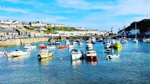 A harbor with numerous boats docked, a waterfront promenade, and buildings in the background. - Captivating 5-bed House in Porthleven (Helston)
