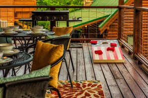 A wooden deck with outdoor furniture, a grill, and a star-patterned table.