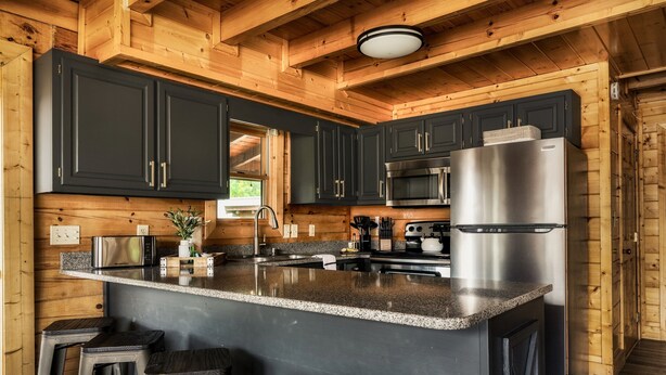 A modern kitchen with dark cabinets, stainless steel appliances, and a granite countertop.