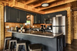 Una cocina moderna con armarios oscuros, electrodomésticos de acero inoxidable y encimera de granito.