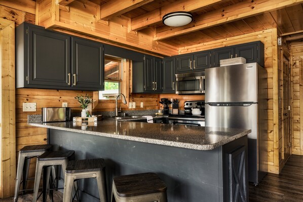 A modern kitchen with dark cabinets, stainless steel appliances, and a granite countertop.