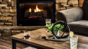 A cozy living room with a stone fireplace, a wooden coffee table, and a comfortable sofa.