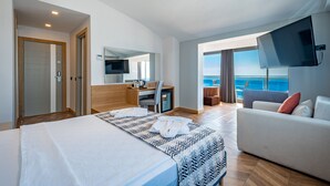 Une chambre d’hôtel moderne dotée d’un grand lit, d’un bureau, d’une télévision et d’un balcon offrant une vue sur la mer.
