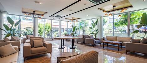 A spacious lobby with multiple seating areas, large windows, and modern lighting fixtures.