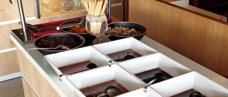 A buffet setup with multiple serving dishes and utensils.