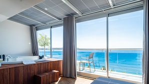 Une salle de bain moderne avec un meuble-lavabo en bois, une grande fenêtre et une vue sur la mer.