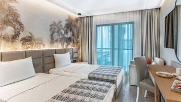 Una habitación de hotel moderna con dos camas, un área de comedor y un ventanal con cortinas.