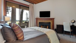 Un dormitorio con una cama grande, una chimenea, un televisor y un escritorio con una silla.