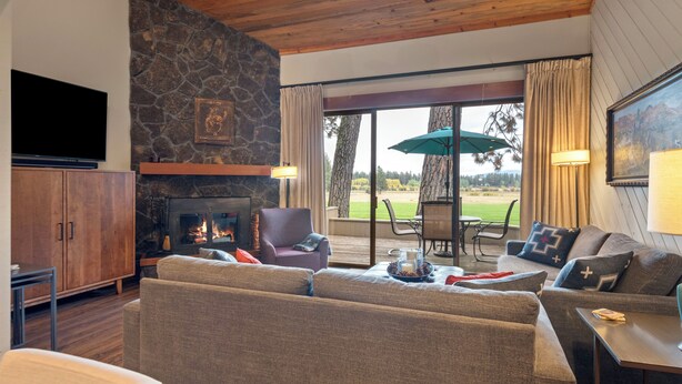 Una sala de estar acogedora con chimenea de piedra, asientos cómodos y un amplio ventanal con vistas panorámicas.