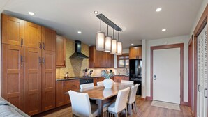 Una cocina moderna con armarios de madera, una mesa de comedor con sillas e iluminación colgante.