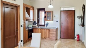 A compact kitchen with wooden cabinets, a built-in oven, and a dining area with a table and chairs. - 2-bed Apartment in Abruzzo, Italy 15 Minute to sea (Paglieta)