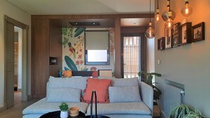 Una sala de estar moderna con un sofá gris, una mesita con una planta y una pared decorada con marcos.