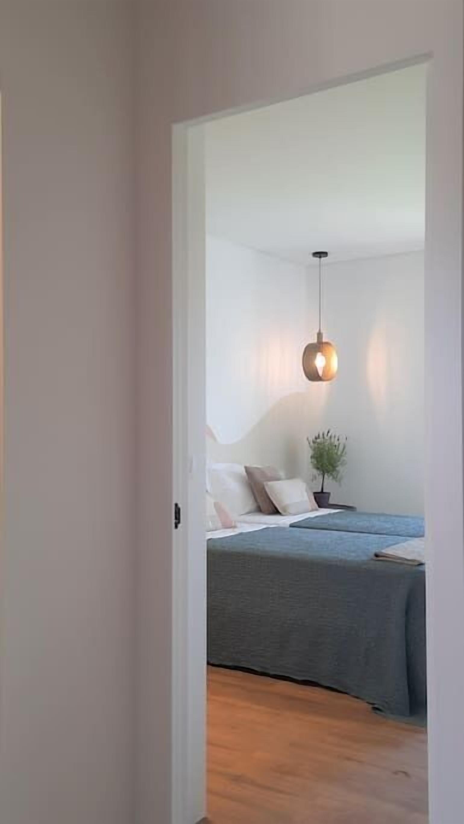 Ein Schlafzimmer mit einem Bett, einer Hängelampe und einer Pflanze.