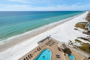 A beachside resort with a pool area, sun loungers, and a view of the ocean.