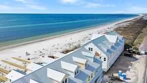 Un hôtel situé en bord de mer, avec un long bâtiment, une plage de sable et l’océan.