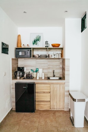 A compact kitchen with a microwave, sink, and a compact refrigerator.