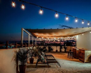 An outdoor patio with a canopy, string lights, lounge chairs, and a bar area. - Stunning studio apartment in the heart of Playa del Carmen (Playa del Carmen)