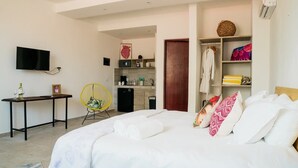 Une chambre comprenant un lit, un bureau, une chaise, un téléviseur et un coin cuisine.